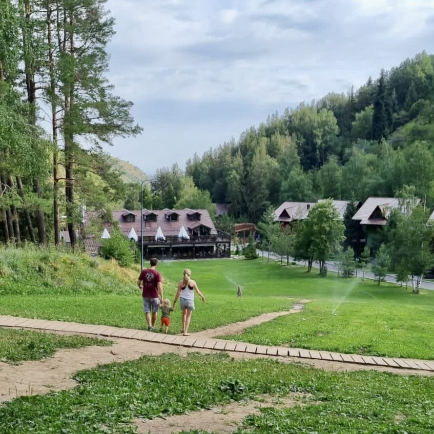 A man and woman walk with a small boy down a green slope