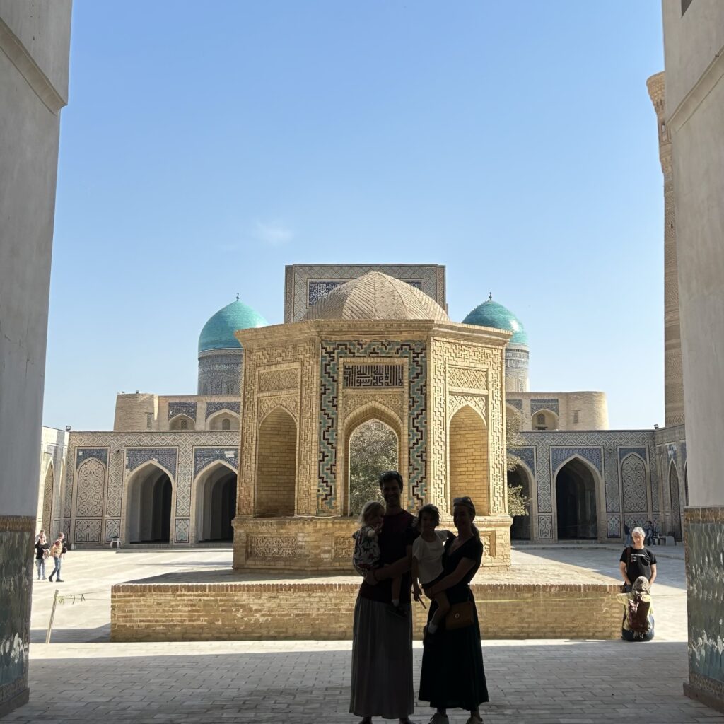 A family stands silhouetted against the bright courtyard of the Madrasah of Emir Alimkhan, in Uzbekistan