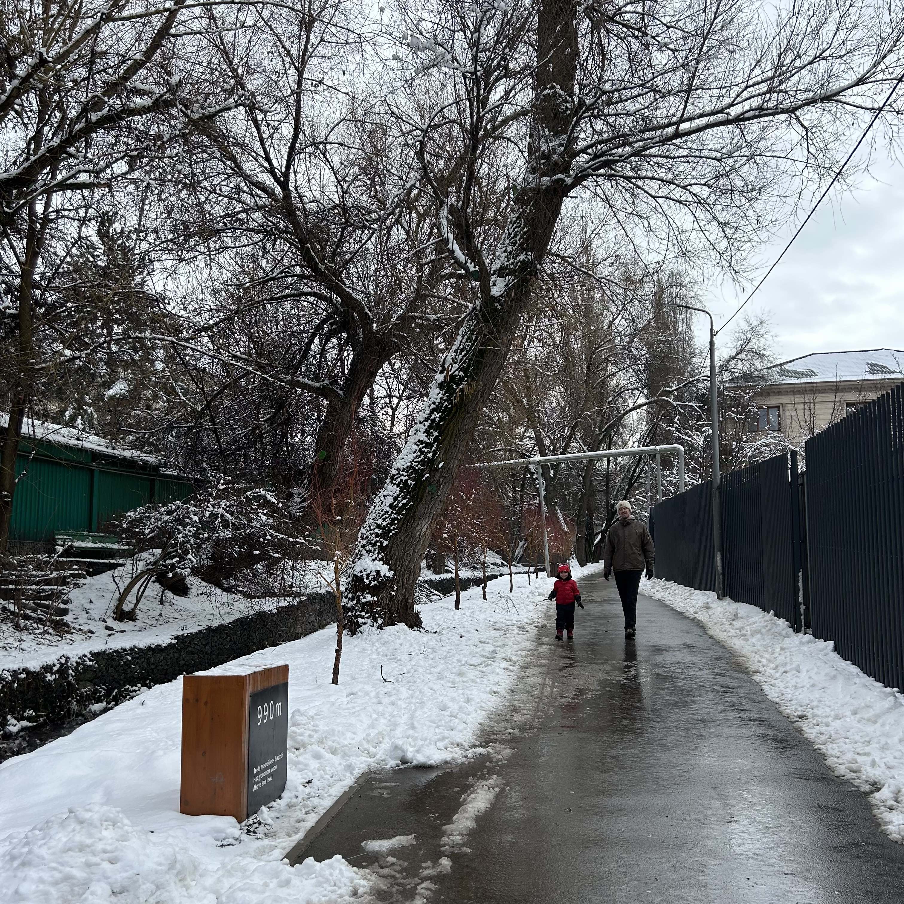 A man and a child walk down a river path with snow around