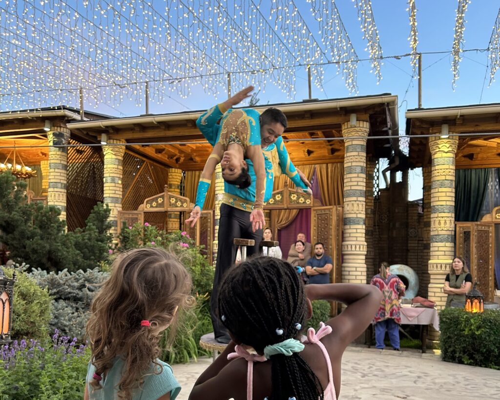 2 girls watch acrobats perform under the stars in the courtyard of Alasha Restaurant, Almaty.