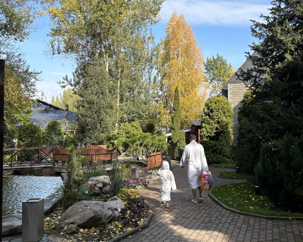 A man and a child walk in their bathrooms through the wooded resort of Tau Dastarkhan in Almaty