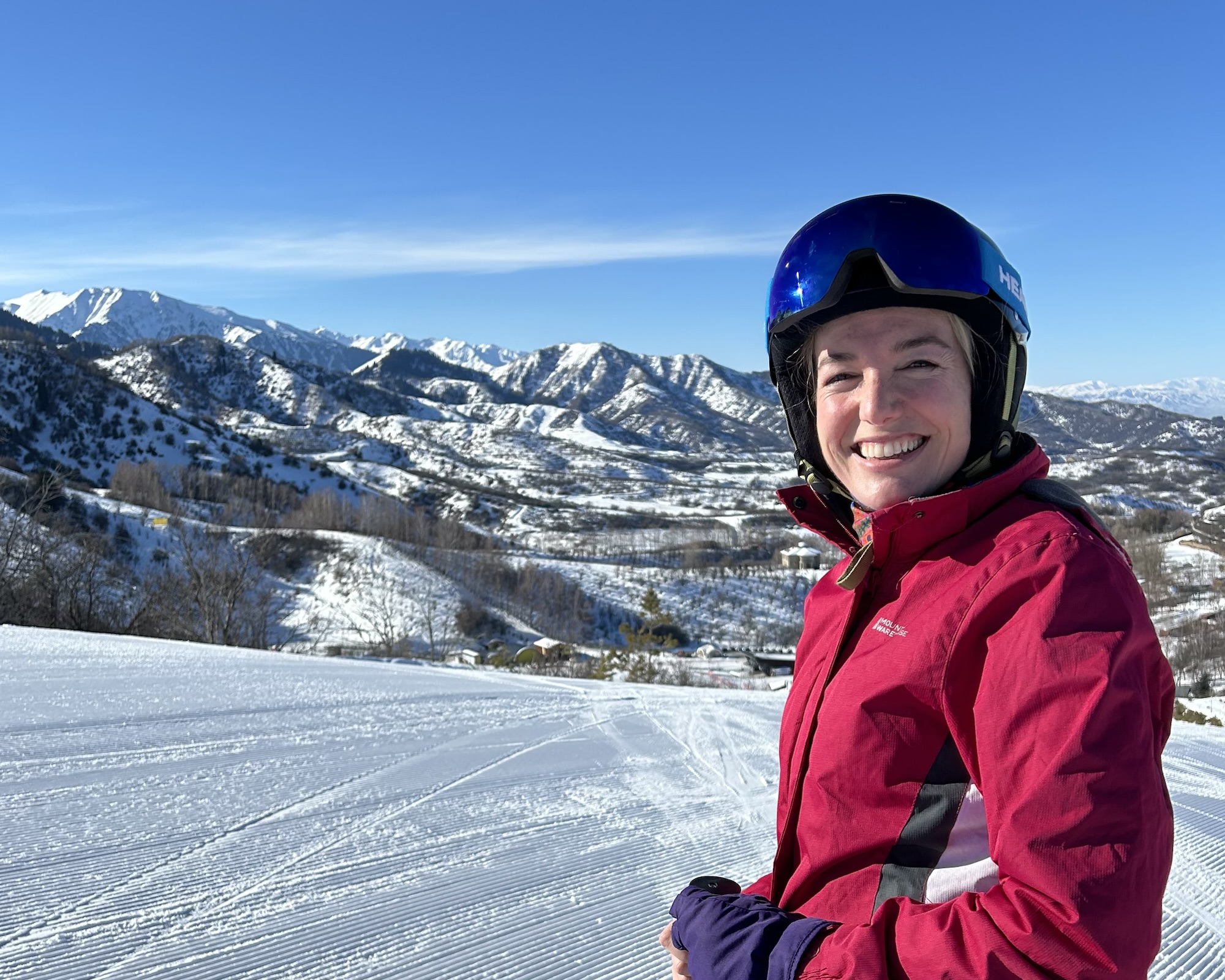 A woman in ski gear stands on front of Oi Qaragai ski resort