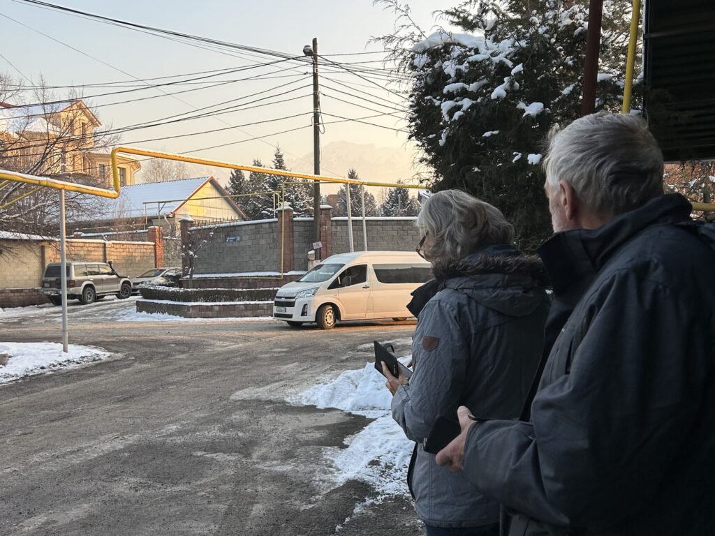 A photo of 2 people waiting on the street as a white van approaches