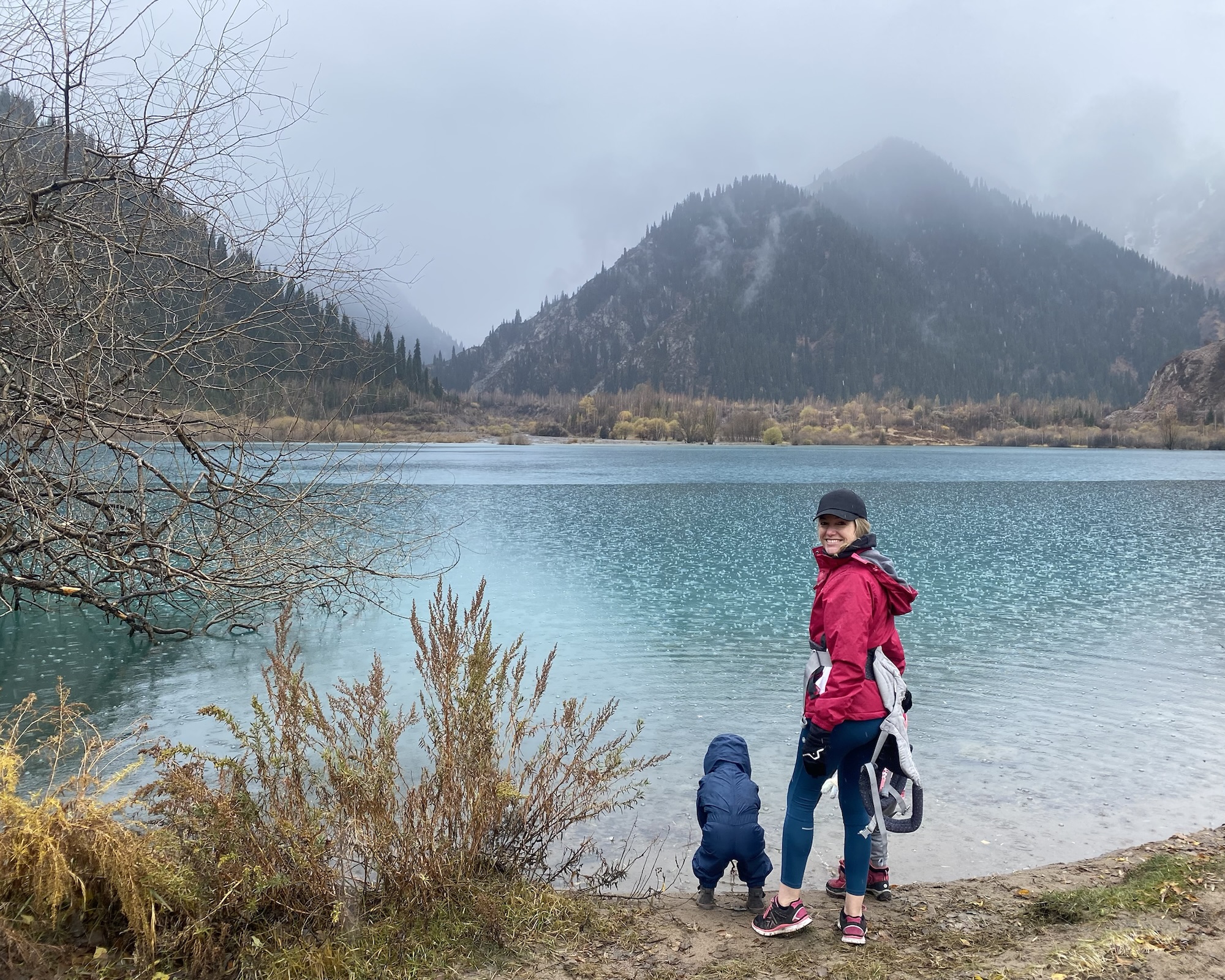 A photo of a woman standing next to Lake Issyk in Kazakhstan with a small child